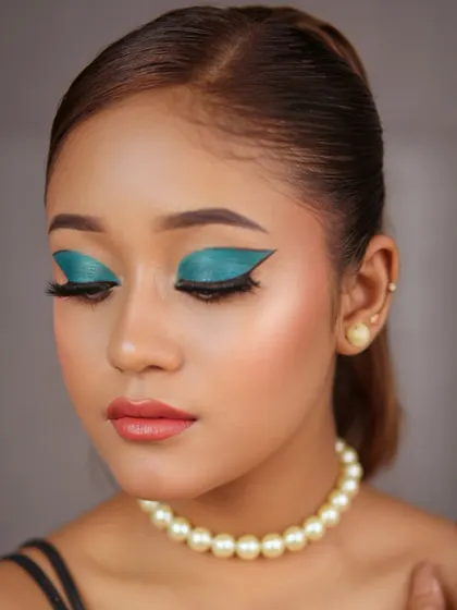 A fusion makeup look featuring a dramatic teal winged eyeshadow. It’s a perfect blend of modern color with classic elegance.