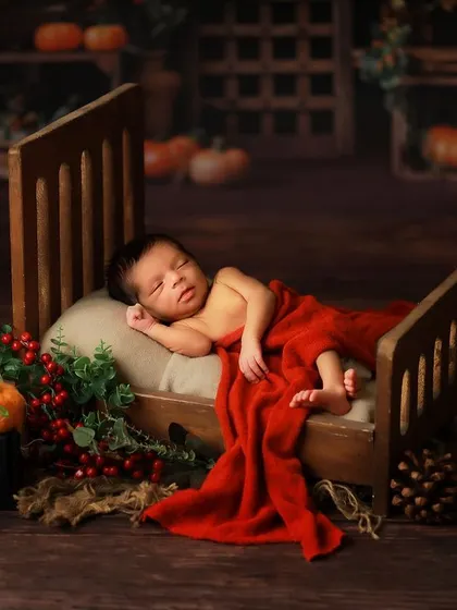 A wider shot of the miniature bed setup, showing the full scene with a rustic backdrop and seasonal props. This demonstrates how we build a complete, picturesque set for your baby.