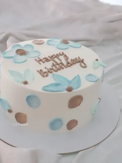 A sweet and simple birthday cake with hand-painted blue and brown flowers and polka dots.