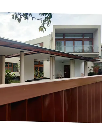 A luxury villa characterized by clean lines and minimalist detailing. The design emphasizes horizontal planes, with a large covered carport and balconies that extend the living space outwards.