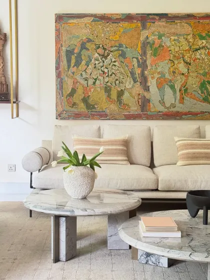 A detail shot from the living room, where modern furniture with clean lines is paired with vibrant, large-scale Indian art. The juxtaposition of minimalist forms and soulful, textured artwork is a key theme in this home's design.