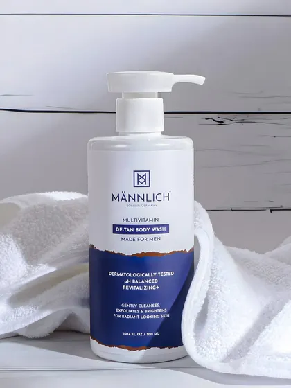 A clean and simple bathroom scene for a men's de tan body wash. The white towel and background create a fresh, hygienic look, focusing on the product's cleansing purpose.