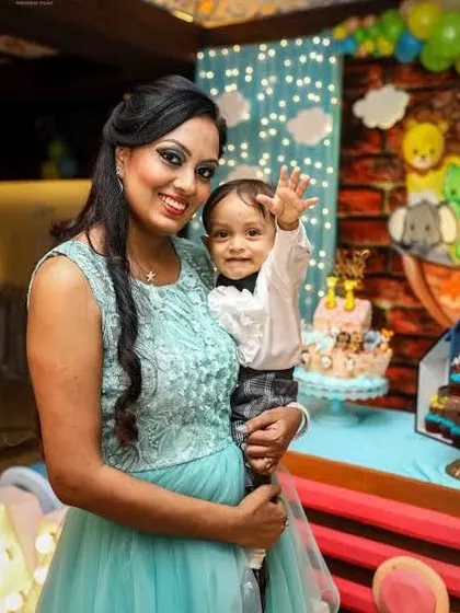 A mother and her baby wave at the camera during a birthday party, capturing a happy, interactive moment.