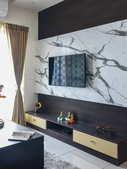 A close-up of the TV unit with a dark wood frame and a white marble-look laminate panel. The design includes contrasting light-colored drawers for a balanced and modern aesthetic.