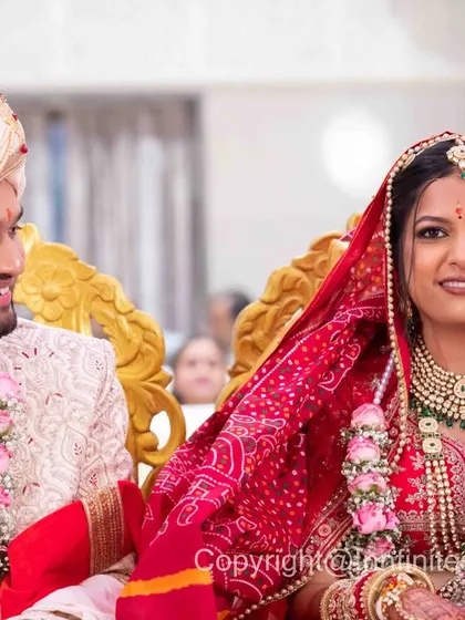 This is a more formal portrait taken during the ceremony. It showcases the couple in their full wedding attire, including the bride's beautiful red Bandhani dupatta.
