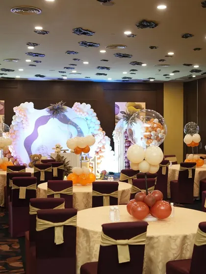 A full view of the hall decorated with teddy bear themed centerpieces. The coordinated decor on the stage and the guest tables creates a complete and immersive party experience.