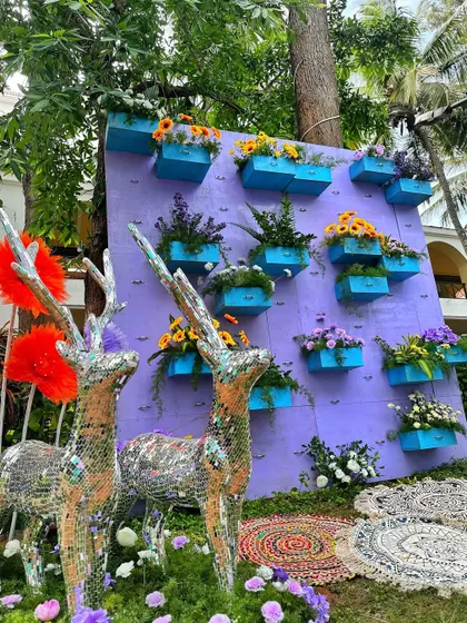 A creative photo installation with mirrored deer statues and a wall of flowers in colorful boxes.