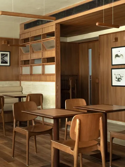 The main seating area at QBF Coffee, where the Japandi aesthetic is fully expressed. The clean lines of the custom wooden furniture, the warm tones, and the considered spacing create a calm, orderly environment.