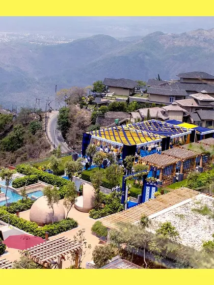An aerial view of a spectacular destination wedding Haldi. The vibrant blue and yellow decor stands out beautifully against the mountain landscape, showcasing our ability to execute large-scale events anywhere.