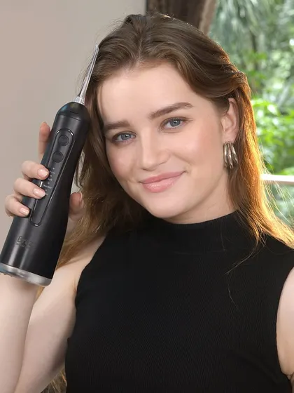 A close-up of the model with the black water flosser, highlighting its sleek design and ease of use.