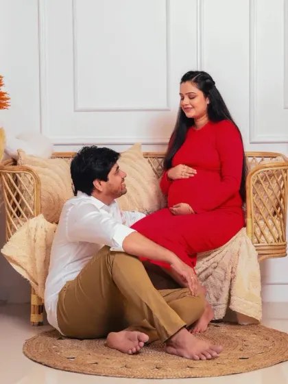 Capturing the conversation between expecting parents. The father-to-be looks up at his partner with adoration in this beautifully lit shot from their boho-themed session.