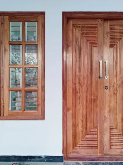 A newly installed main door with a modern geometric carved pattern, paired with a classic wooden window. This photo from one of our sites highlights our expertise in custom woodwork and entry design.