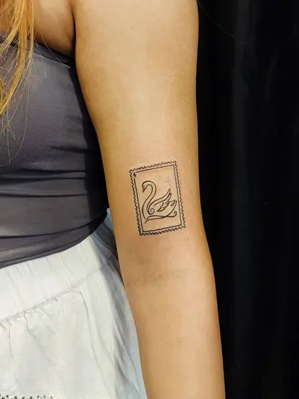 A unique postage stamp tattoo featuring a swan. This creative, fine-line design is a nod to travel and elegance, framed in a classic stamp border.