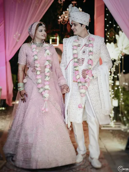 The couple, adorned with beautiful varmalas, holds hands as they walk together after the ceremony. A perfect shot of the newlyweds.