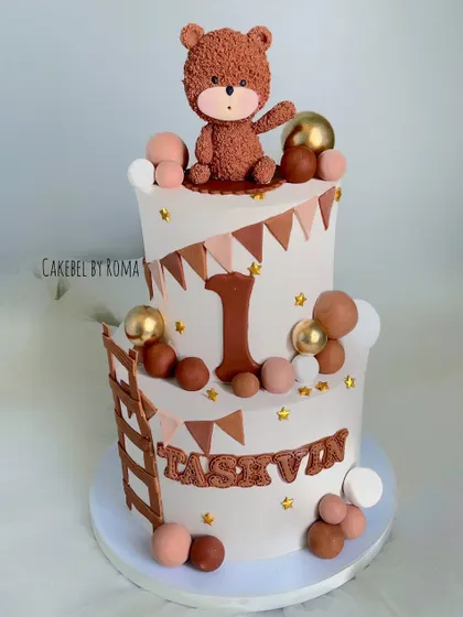 A charming two-tier woodland teddy bear cake for Tashvin's first birthday. The neutral brown and beige tones, along with the cute bear topper, create a warm and rustic feel.