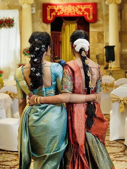 A back view showcasing the beautiful, traditional hairstyles for the half saree ceremony. Intricate braids adorned with flowers are a key part of the look.
