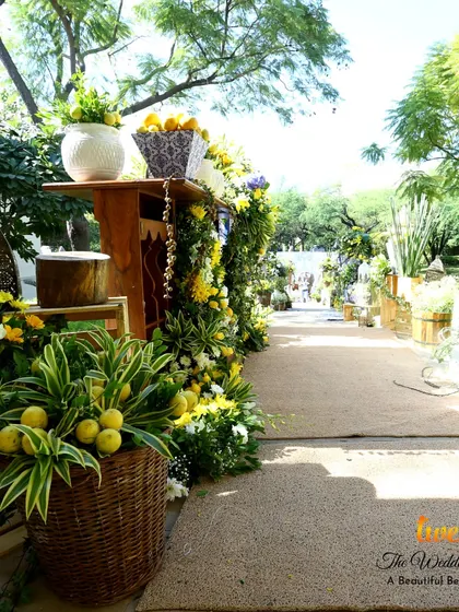 A beautiful walkway for a daytime event, lined with baskets of lemons and fresh flowers, perfectly executing the Tuscan theme.
