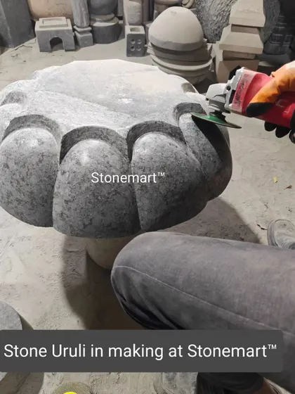 An artisan carves the petal-like details on a large stone uruli.