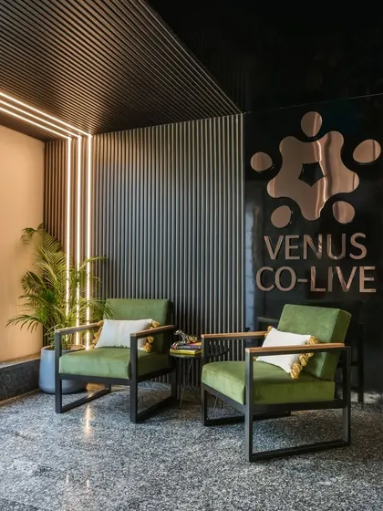 This cozy conversation nook at Venus Co-Live uses comfortable armchairs, warm lighting, and textured wall panels to create an inviting corner for informal chats or a quiet moment away from the main work floor.