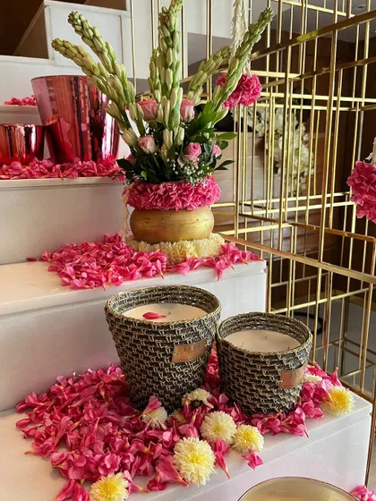 A detail shot of the festive stair decor, showing candles in woven baskets and scattered pink petals. These small touches add warmth and a handcrafted feel to the celebration.