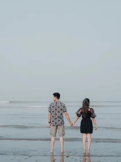 A minimalist pre-wedding shot of a couple holding hands and looking out at the ocean, creating a feeling of shared dreams.