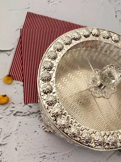 A keepsake box that does more than hold, it delights. This ornate silver-plated piece with a crystal knob is perfect for dry fruits, sweets, or little festive treasures.