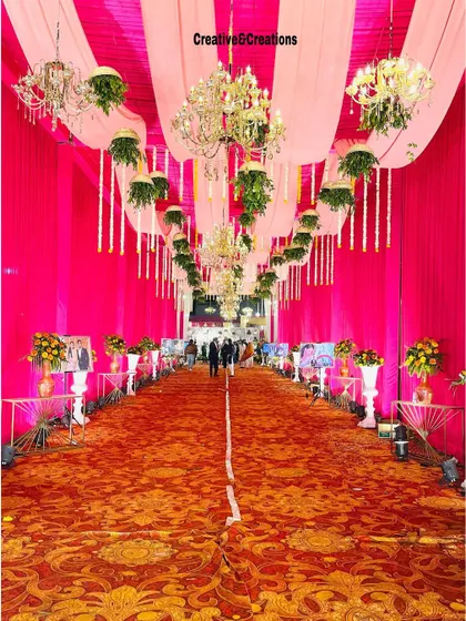 A still image capturing the grandeur of the pink and red wedding aisle. The scale of the decor, with its high ceilings and numerous chandeliers, is truly impressive.