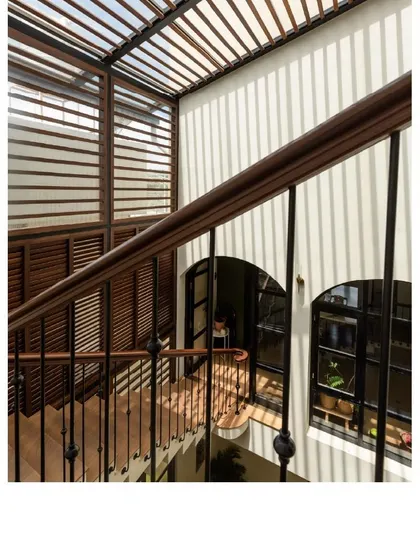 From the staircase, you can see how the slatted roof filters sunlight, casting beautiful patterns on the walls. This passive design element helps keep the space cool and bright.