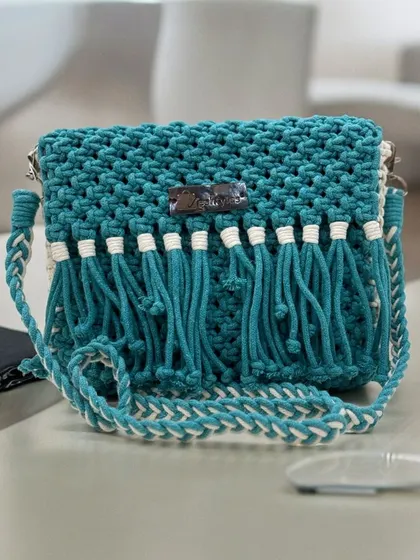 This teal sling bag with a two-tone strap is so unique. The fringe detail adds beautiful movement to the design.