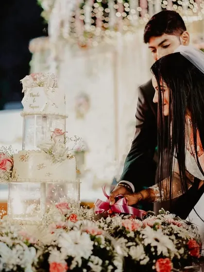 The cake cutting ceremony is the first sweet task a couple performs together. This shot captures that moment, surrounded by a beautiful floral arrangement, marking the start of their sweet new life.
