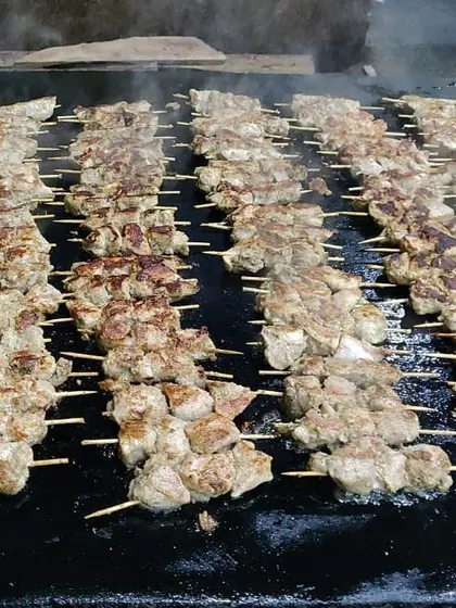 Rows of chicken malai sticks being grilled to perfection on a large flat-top. This is part of our live kebab counter, ensuring fresh and smoky appetizers for everyone.