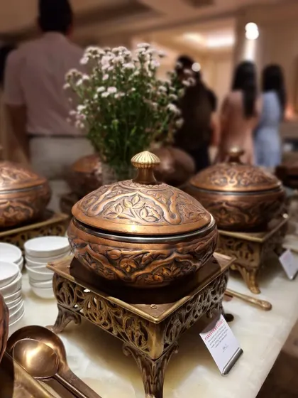Our exclusive Mughlai dinner setup featuring ornate, hand-embossed copper and brass serving dishes. This attention to detail in our serveware elevates the dining experience, creating a royal and authentic ambiance for your special occasion.