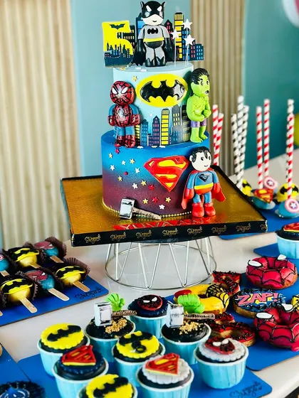 Avengers, assemble. This epic superhero dessert table features a multi tiered cake with Batman, Superman, Spider-Man, and the Hulk. The setup is complete with matching cupcakes, donuts, and cakesicles.