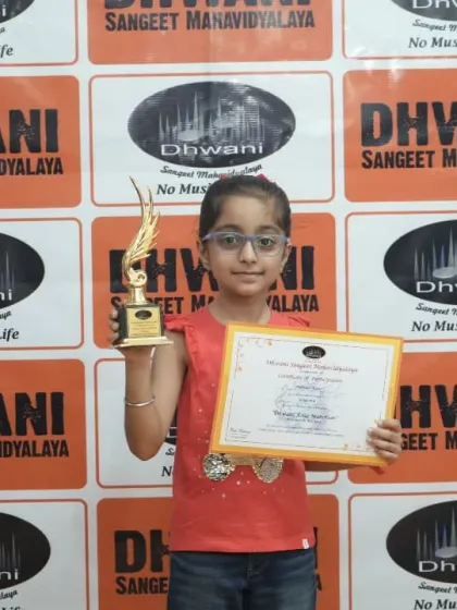 A young girl proudly displays her certificate and trophy.