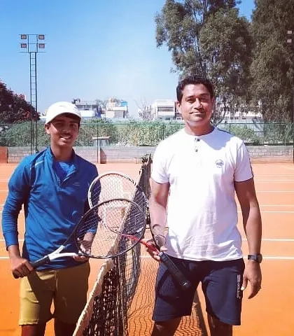 Two competitors in the Tennis360 Open Tournament pose for a photo at the net after their match.