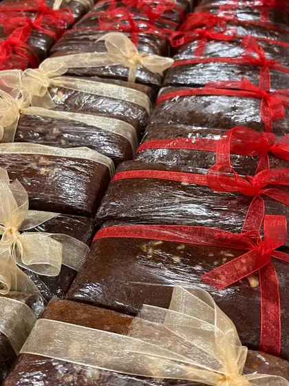 Rows of our rich, dark Christmas fruit cakes, wrapped and tied with festive ribbons. These are a labour of love and a holiday tradition.