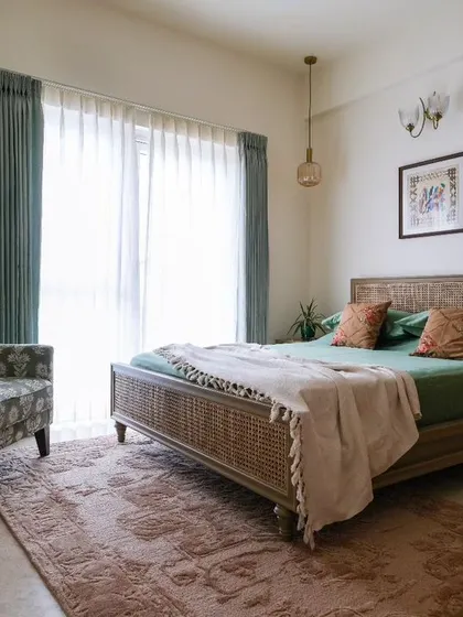 The master bedroom, designed as a calm oasis with earthy tones, wood, and rattan. A classic wing chair was revamped with a vibrant floral green fabric to create a perfect spot to unwind.