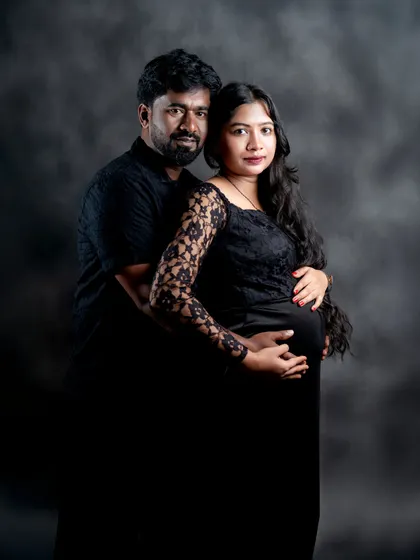 A classic, moody studio portrait of a couple. The dark attire and background create a dramatic and intimate feel, focusing on their connection.