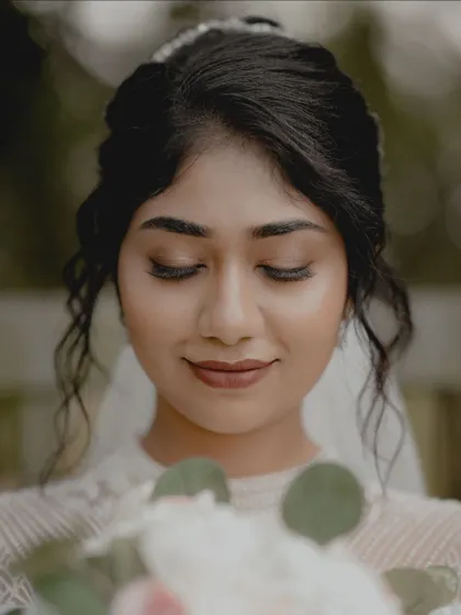 An intimate close-up of a Christian bride looking down at her bouquet, highlighting her serene makeup and hairstyle.