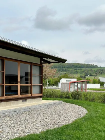 A detail of the Umbrella House's facade, showing the simple, elegant woodwork and its connection to the landscape.