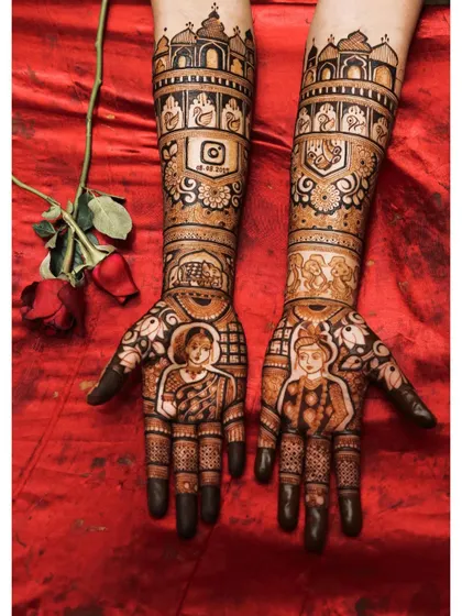 Your mehendi is a key part of your bridal look. This design shows how custom portraits and story elements, like the Instagram logo with a special date, come together against a beautiful red lehenga.