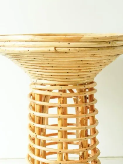 A close-up of our flared rattan pedestal table or stand. The combination of a tightly coiled top and an open-weave base creates a visually interesting piece, ideal for displaying a plant or a decorative object.