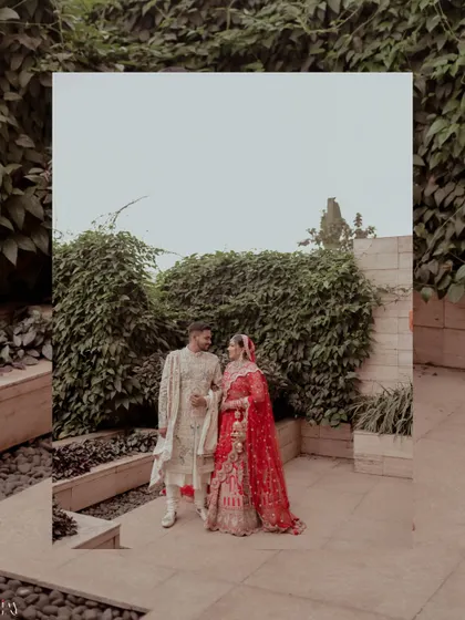 A creative shot of the couple framed within a reflection, set against a lush green wall.