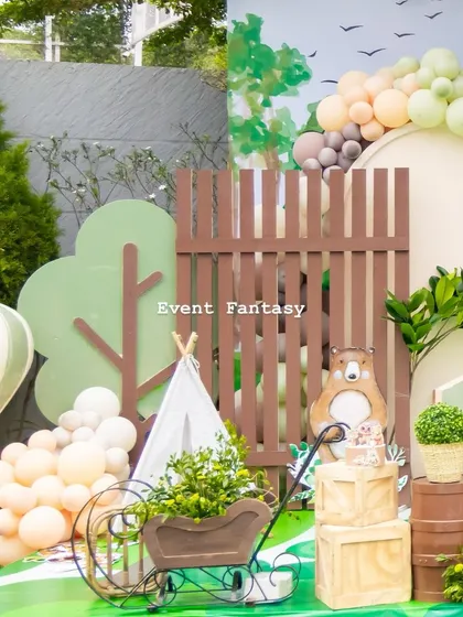 A detailed view of the woodland setup, showing a miniature teepee, a wooden cart filled with plants, and a bear cutout in the background.