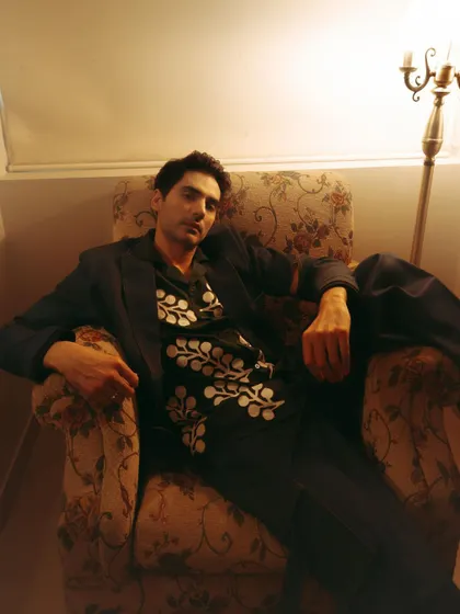 A relaxed portrait of Ishwak Singh for Hindustan Times, seated in a vintage armchair under warm, ambient light.