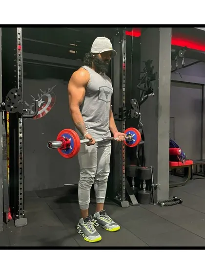 Work harder than yesterday. Performing a standing barbell curl to develop overall arm mass and strength.