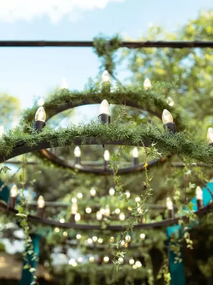 Looking up at the custom-made chandeliers adorned with greenery. These structures added a touch of rustic elegance and provided warm lighting as the sun set.