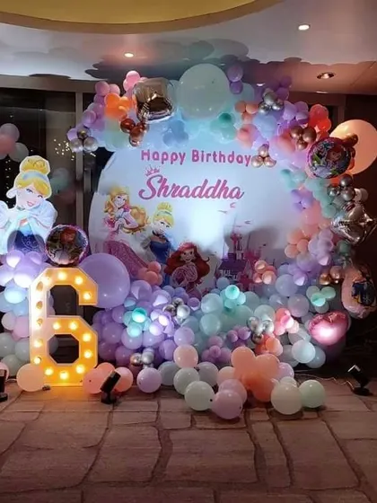 A dreamy Disney Princess theme for a 6th birthday. This decoration features a large backdrop, a Cinderella cutout, a marquee number '6', and a pastel balloon arrangement.