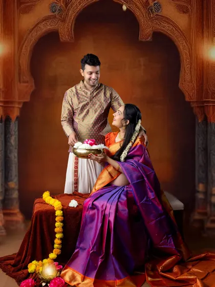 A beautiful moment from a traditional baby shower or 'Godh Bharai' themed shoot. The couple shares a happy moment in a setting filled with cultural details like marigold garlands.