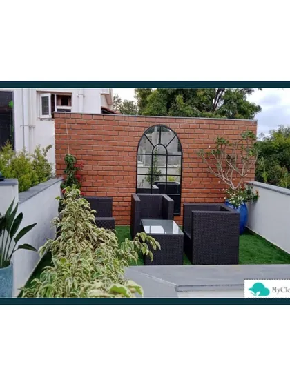 To add warmth and texture to this terrace, I designed a prominent brick accent wall. This feature, combined with modern black outdoor furniture and artificial grass, creates a contemporary yet cozy atmosphere perfect for an urban setting.
